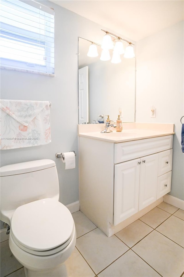 half bathroom featuring tile patterned flooring, toilet, vanity, and baseboards