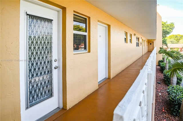 entrance to property featuring a balcony and stucco siding