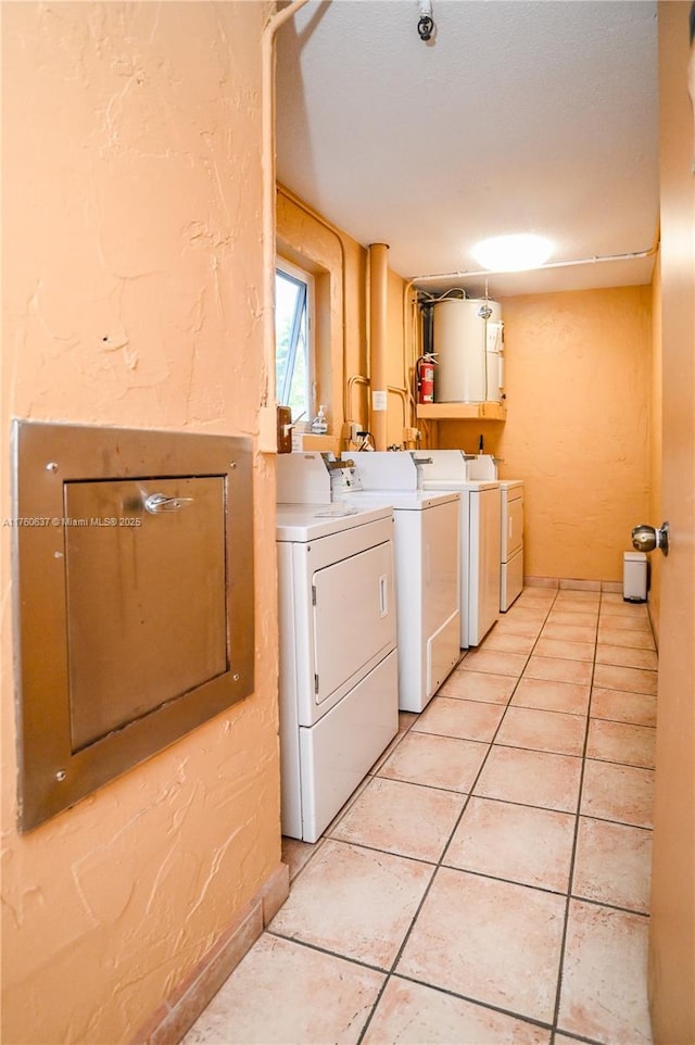 clothes washing area with light tile patterned floors, laundry area, gas water heater, a textured wall, and independent washer and dryer