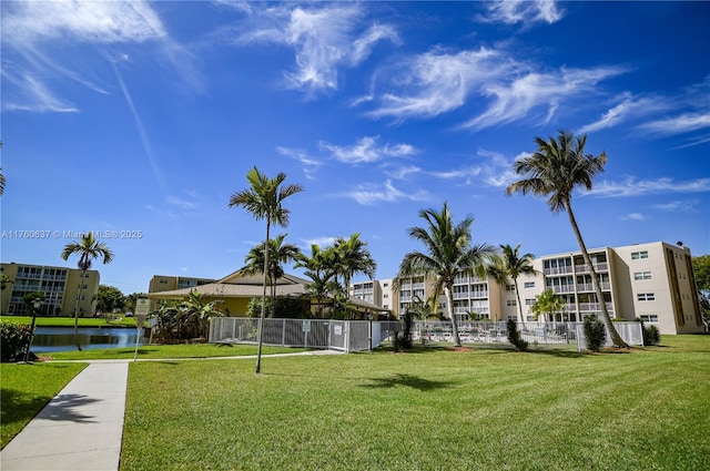 surrounding community with a lawn, fence, and a water view