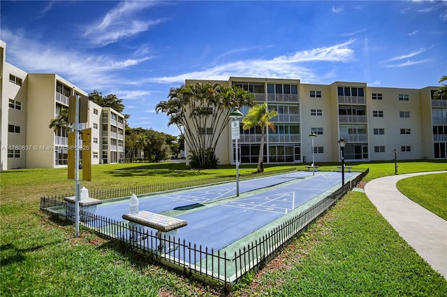 view of home's community featuring shuffleboard, a lawn, and fence