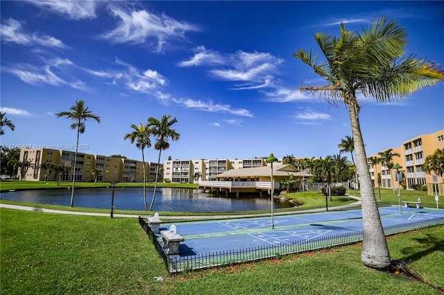 exterior space with shuffleboard, a yard, and a water view