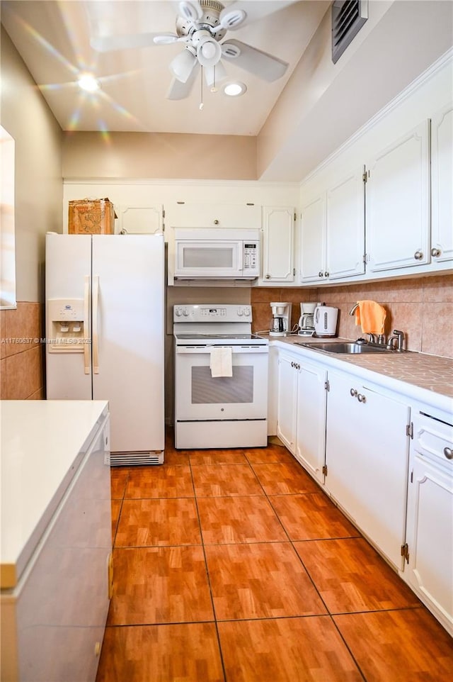 kitchen with white appliances, light tile patterned floors, a ceiling fan, a sink, and white cabinets