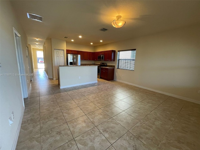 kitchen featuring visible vents, appliances with stainless steel finishes, open floor plan, and reddish brown cabinets