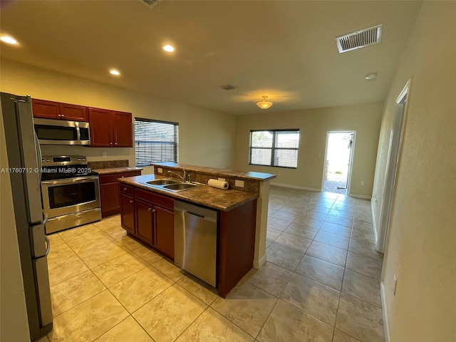 kitchen featuring dark countertops, visible vents, a sink, stainless steel appliances, and reddish brown cabinets