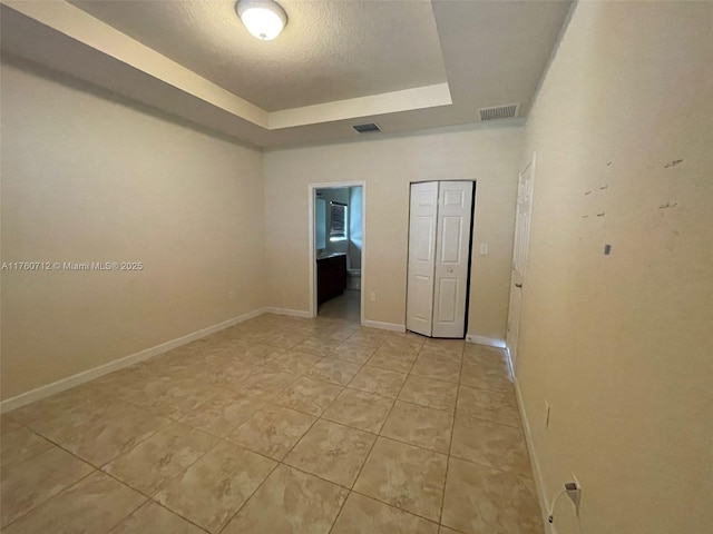 unfurnished room with visible vents, a raised ceiling, and baseboards