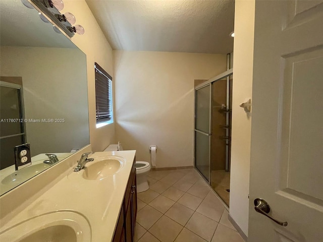 bathroom with tile patterned floors, a shower stall, and a sink