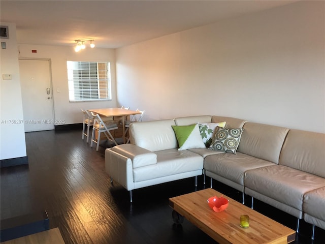 living area with visible vents, baseboards, and wood finished floors