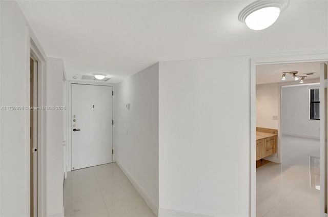 corridor with light tile patterned floors and baseboards