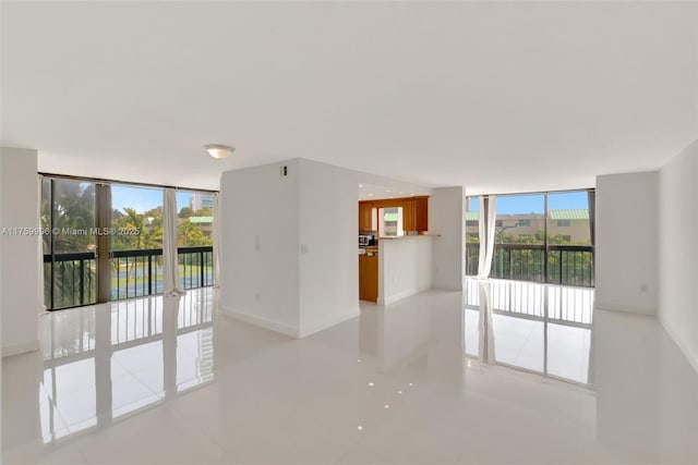 spare room featuring baseboards, plenty of natural light, and floor to ceiling windows