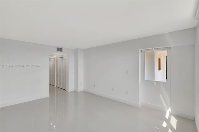 empty room with visible vents, baseboards, and concrete flooring