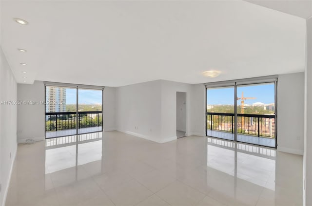 unfurnished room with floor to ceiling windows, baseboards, and a wealth of natural light