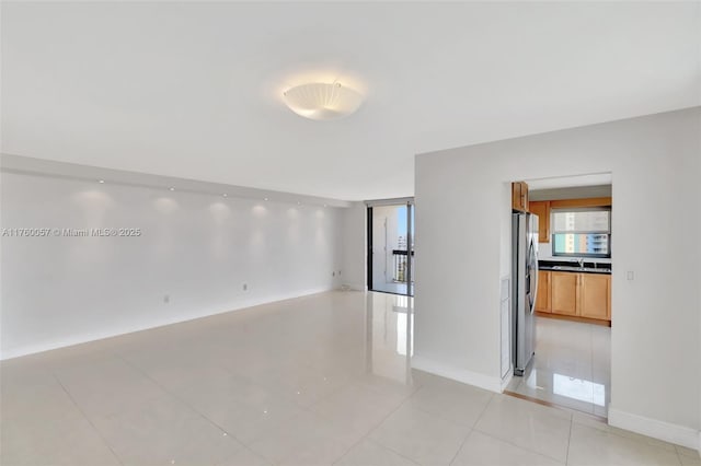 spare room with a sink, baseboards, and light tile patterned flooring