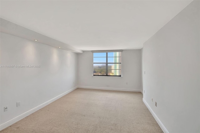 unfurnished room featuring baseboards and light carpet