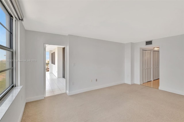 empty room with light colored carpet, visible vents, and baseboards