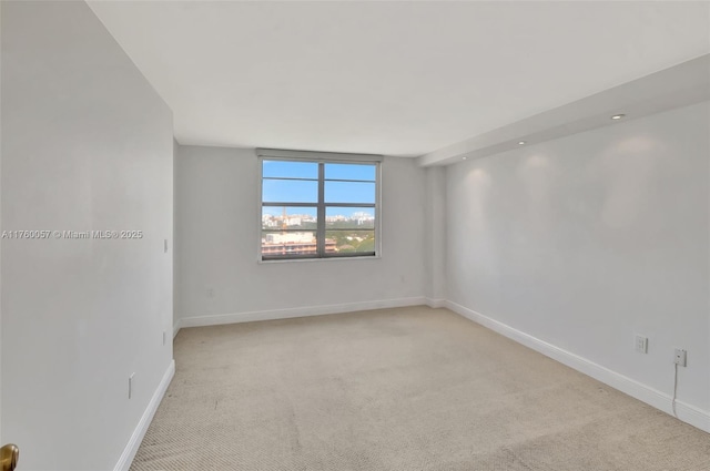 empty room featuring baseboards and light colored carpet