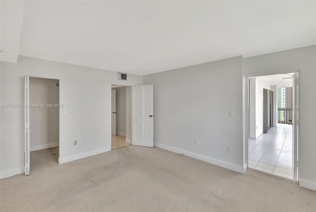 unfurnished bedroom with visible vents, light carpet, baseboards, and a spacious closet