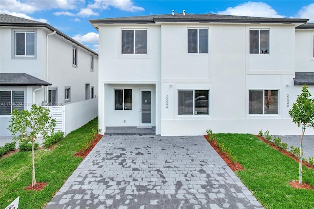 back of property featuring stucco siding, a patio, a lawn, and fence