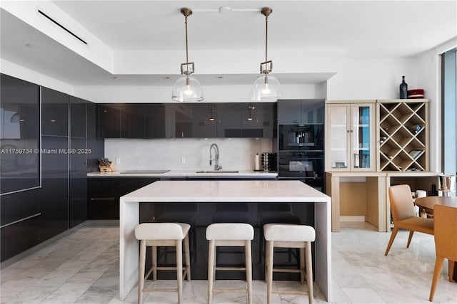 1451 Brickell Ave Unit 4002, Miami, FL 33131 - kitchen with light marble finish floors, modern cabinets, a breakfast bar area, dark cabinets, and backsplash