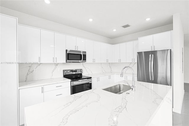 kitchen with visible vents, white cabinetry, stainless steel appliances, and a sink