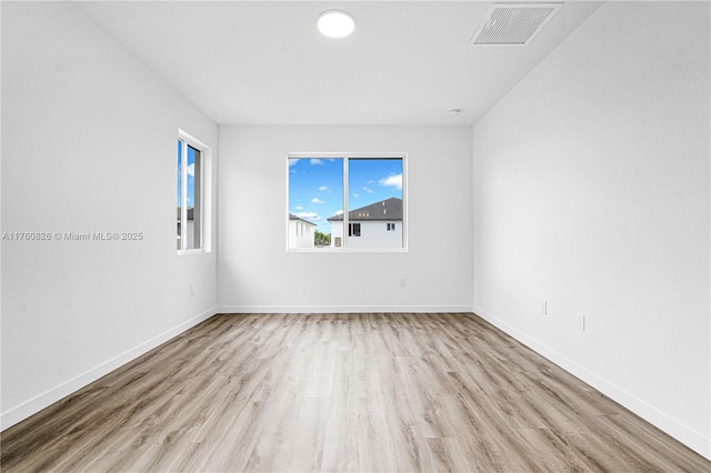 spare room featuring visible vents, baseboards, and wood finished floors