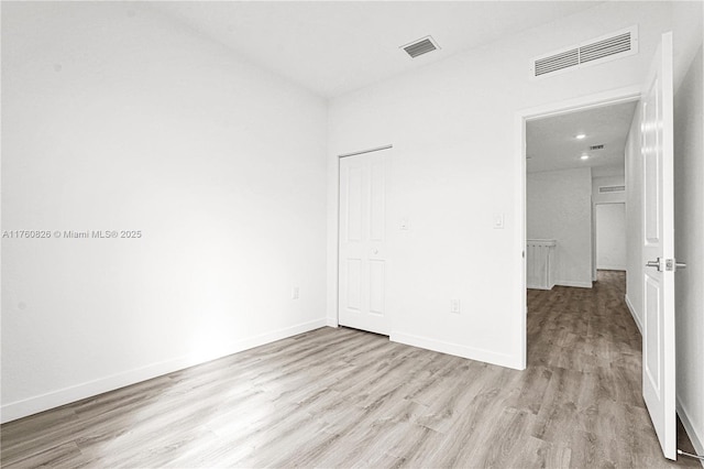 unfurnished bedroom with wood finished floors, visible vents, and baseboards