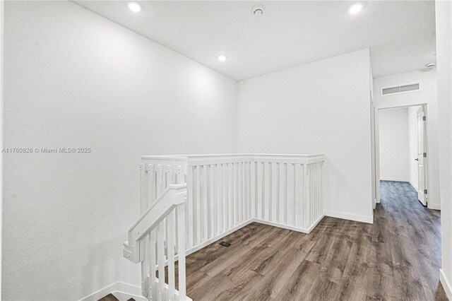 hallway with visible vents, baseboards, an upstairs landing, recessed lighting, and wood finished floors