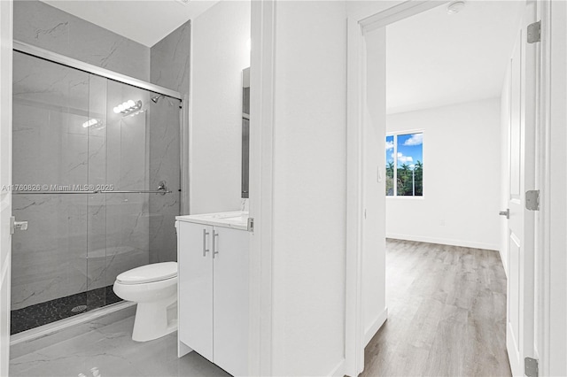 bathroom with a marble finish shower, toilet, vanity, and wood finished floors