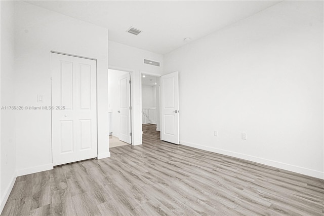 unfurnished bedroom with visible vents, baseboards, a closet, and wood finished floors