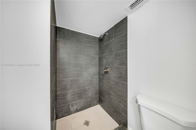 full bathroom featuring a tile shower, visible vents, and toilet