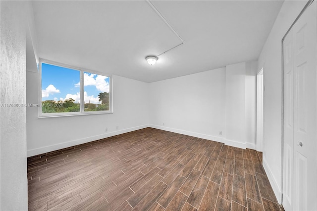 empty room with baseboards and dark wood finished floors