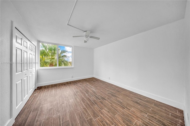 interior space with a ceiling fan, baseboards, and dark wood-style flooring