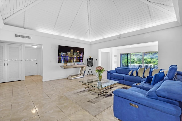 living room with light tile patterned floors, visible vents, high vaulted ceiling, and baseboards