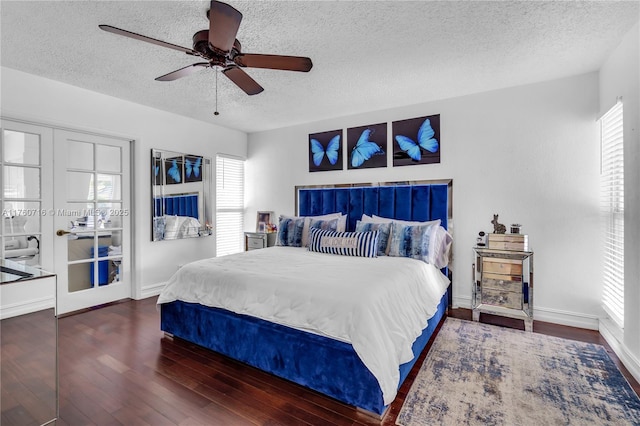 bedroom with multiple windows, a textured ceiling, baseboards, and wood finished floors