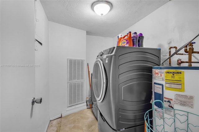 laundry area featuring tile patterned floors, washer and clothes dryer, a textured ceiling, water heater, and laundry area