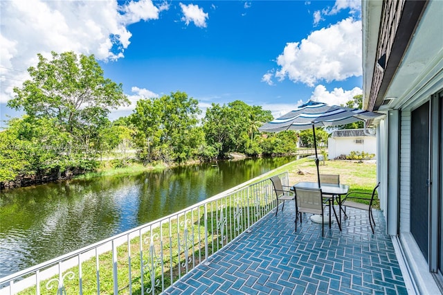 balcony featuring outdoor dining area and a water view