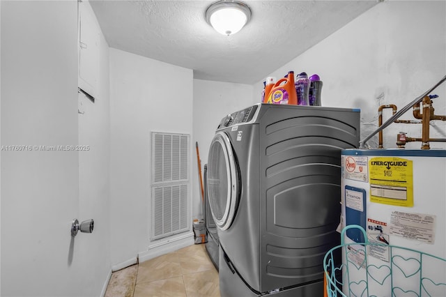 clothes washing area with a textured ceiling, laundry area, tile patterned floors, water heater, and washer and clothes dryer