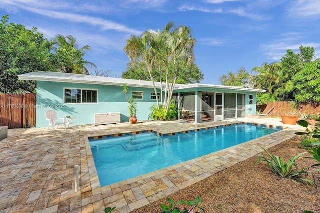 back of house with stucco siding, fence, a sunroom, a fenced in pool, and a patio area