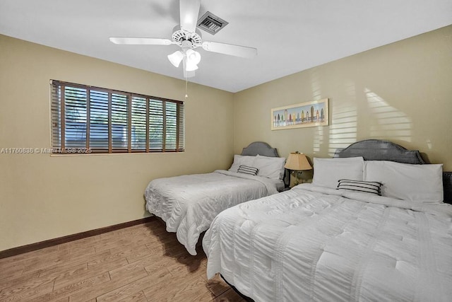 bedroom with ceiling fan, visible vents, baseboards, and wood finished floors