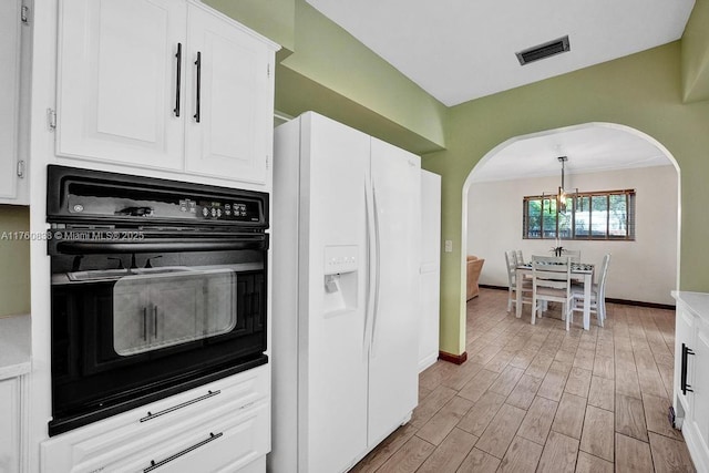 kitchen with oven, light wood-style floors, white fridge with ice dispenser, arched walkways, and white cabinets