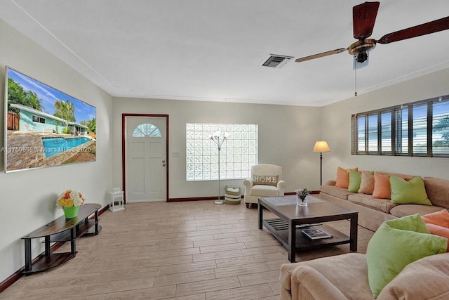 living area featuring light wood-type flooring, visible vents, baseboards, and a ceiling fan