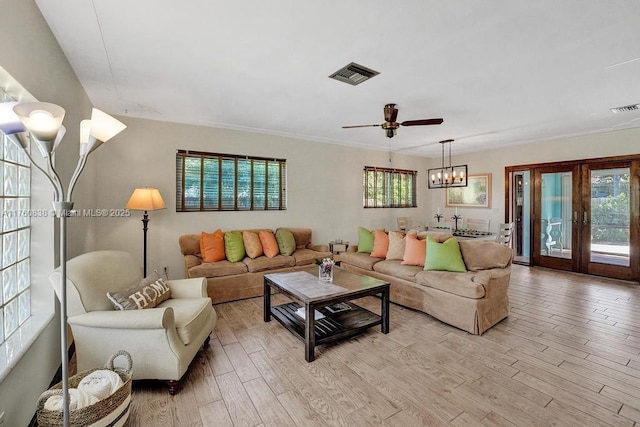 living area featuring french doors, ceiling fan with notable chandelier, visible vents, and light wood finished floors