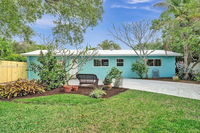 view of front of home featuring a patio area, a front lawn, fence, and stucco siding