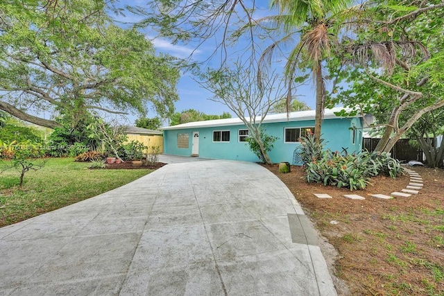 single story home featuring stucco siding, concrete driveway, a front yard, and fence