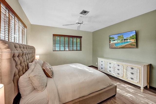 bedroom with a ceiling fan, wood finished floors, visible vents, and baseboards