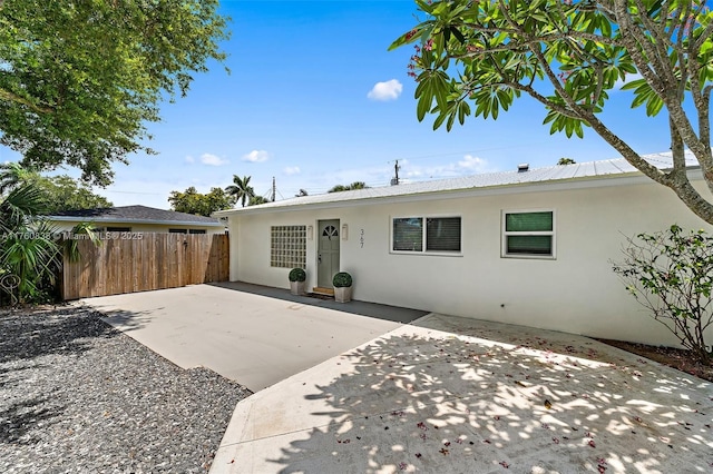 367 W Riverside Dr, Tequesta, FL 33469 - view of front of property featuring stucco siding, a patio, and a metal roof