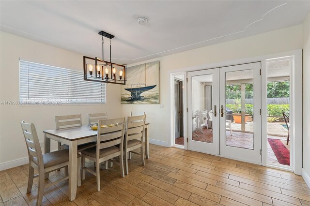 367 W Riverside Dr, Tequesta, FL 33469 - dining area featuring light wood-style floors, a chandelier, and french doors