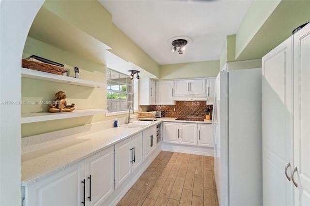 367 W Riverside Dr, Tequesta, FL 33469 - kitchen with freestanding refrigerator, under cabinet range hood, white cabinets, light wood-style flooring, and light stone counters