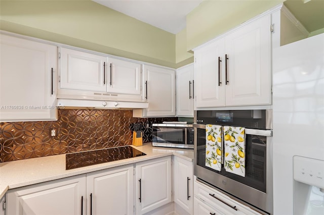 367 W Riverside Dr, Tequesta, FL 33469 - kitchen with appliances with stainless steel finishes, decorative backsplash, white cabinetry, and extractor fan
