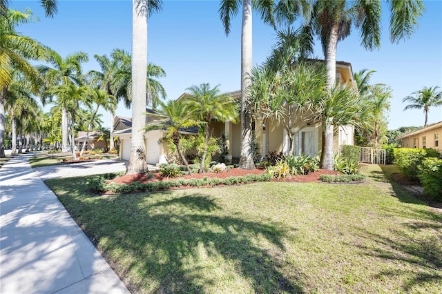 view of front facade featuring stucco siding, concrete driveway, and a front lawn